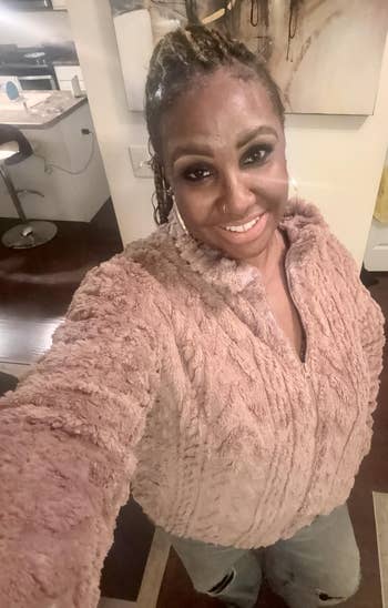 Person successful  cozy textured jacket, smiling indoors