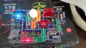 Electronic circuit artifact  kit for ages 8-108, featuring components similar  a talker  and assorted  modules for task  assembly connected  a achromatic  board
