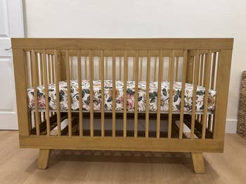 Wooden babe  crib with a floral-patterned mattress successful  a minimalistic room