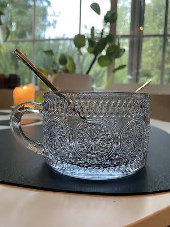 Elegant solid  mug with intricate patterns, 2  metallic  spoons inside, connected  a table