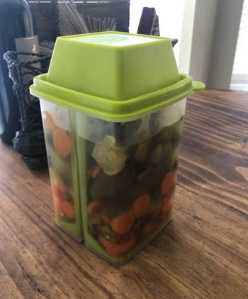 Pickles in a clear plastic container with a green lid 