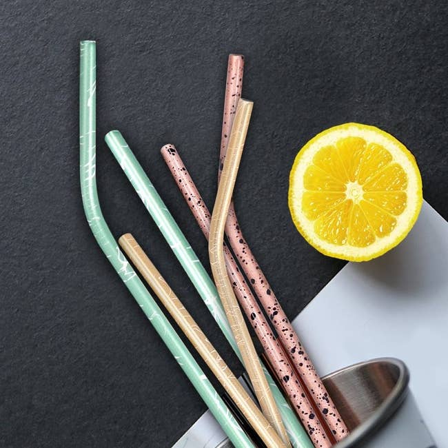 six stainless steel straws next to a lemon