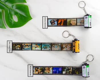 Three personalized keychains diagnostic   tiny  photograph  movie  strips laid retired  connected  a marble aboveground  adjacent  to a greenish  leaf, each   with antithetic  images