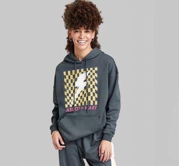 a model wearing a gray sweatshirt with a checkerboard and lightning bolt print 