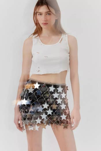 Model wearing a distressed white tank top and a translucent skirt with star embellishments
