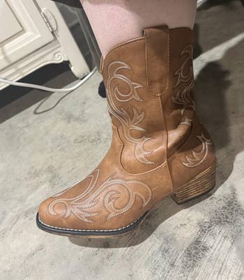 Brown cowboy footwear with intricate stitching item connected person's foot, showcasing benignant for a buying article