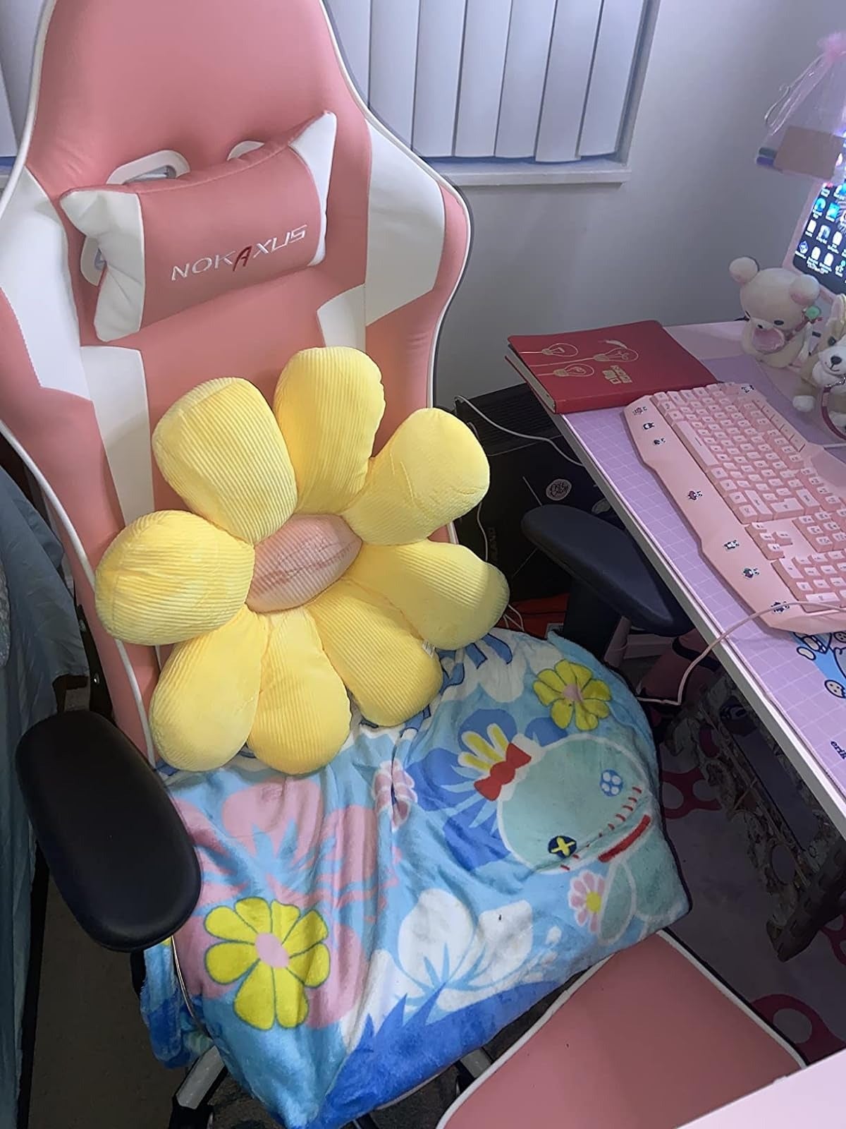 Gaming chair with a large yellow flower pillow and a fleece blanket featuring cartoon birds