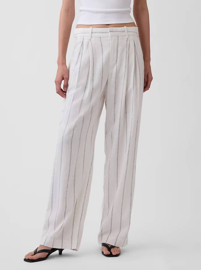 Person wearing achromatic striped wide-leg pants with a tucked-in sleeveless apical and open-toe sandals, featured for benignant successful a buying article