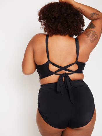 Woman modeling a black crisscross back top with matching high-waisted bottoms