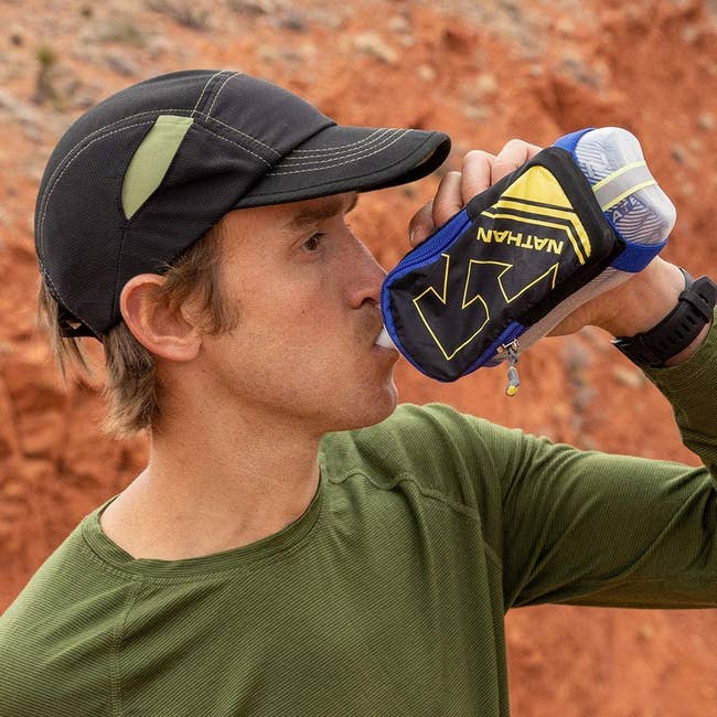 model holds blue handheld insulated water flask while out on a run