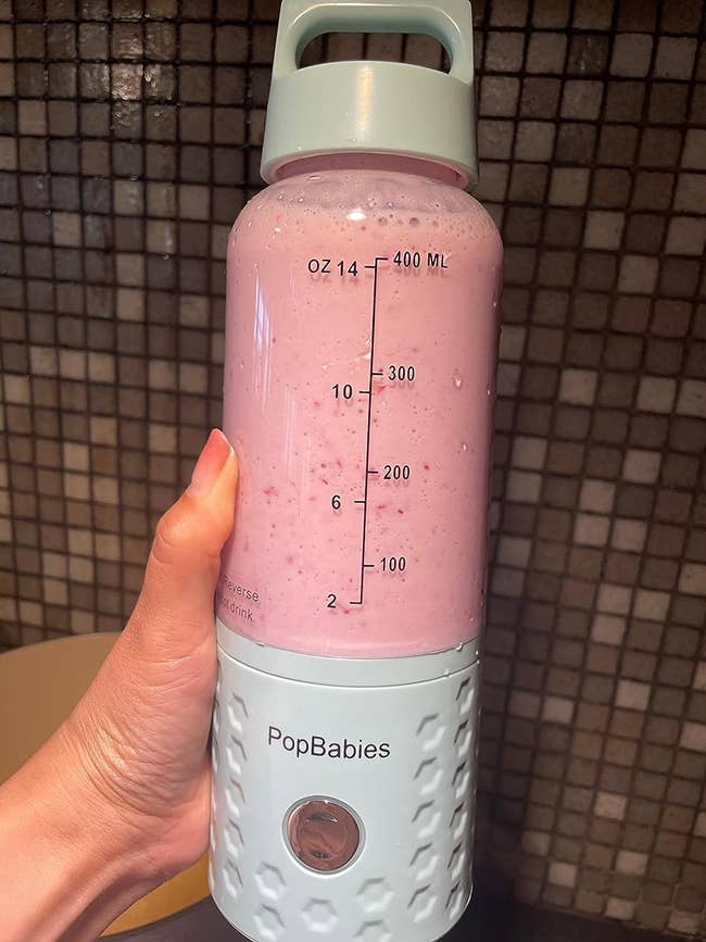 image of reviewer holding up the blender which is full of a pink smoothie