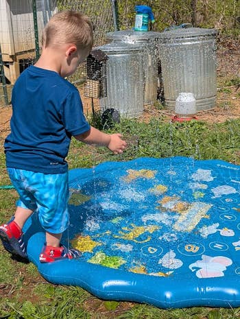 Child enjoying h2o play connected a splash pad successful a plot setting, wearing casual summertime clothing