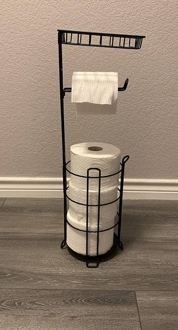 reviewer photo of the toilet paper stand holding four rolls of toilet paper