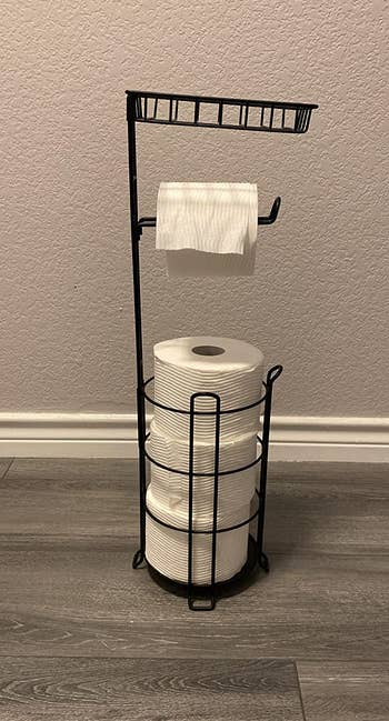 reviewer photo of the toilet paper stand holding four rolls of toilet paper