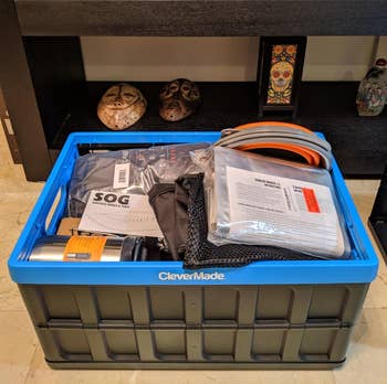 Storage bin with emergency supplies including a knife, flashlight, and cables on a shelf with decorative skulls