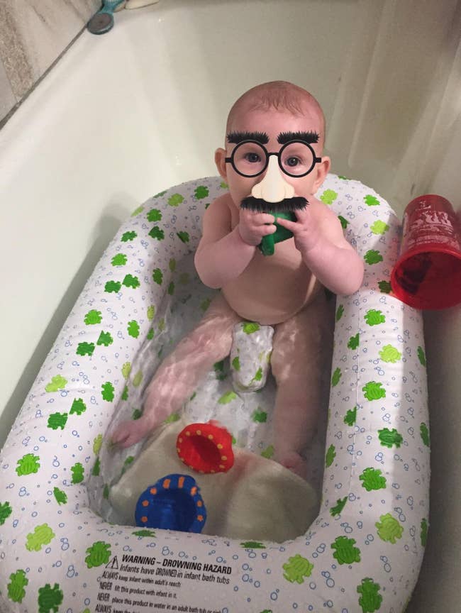 baby sitting in an inflatable tub in a bath tub