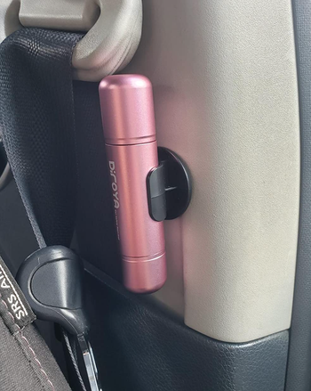 A pink cylindrical device mounted to a car interior 