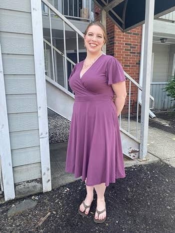 Reviewer smiling successful beforehand of a staircase, wearing a casual, knee-length V-neck formal and sandals