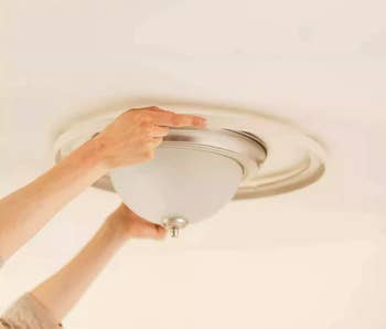 Person's hand installing a ceiling light fixture