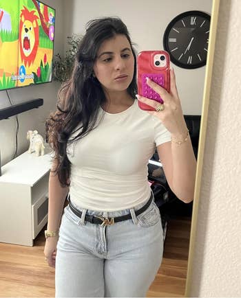 Person taking a reflector  selfie wearing a achromatic  t-shirt and airy  jeans, holding a telephone  with a pinkish  lawsuit  featuring a pop-it toy