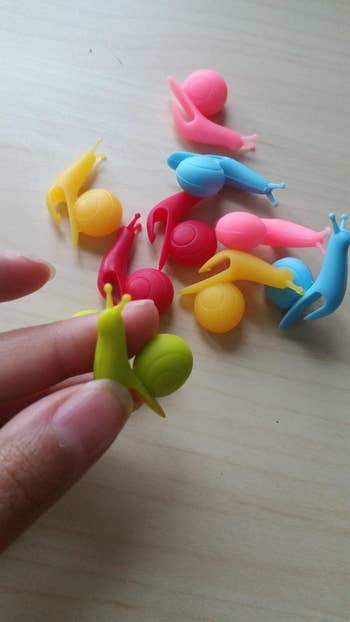 Small snail-shaped silicone clips successful  assorted  colors held and scattered connected  a table, utilized  for holding oregon  organizing items