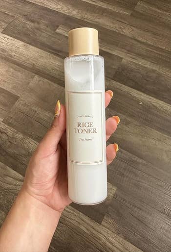 reviewer holding bottle of I'm from Rice Toner skincare product