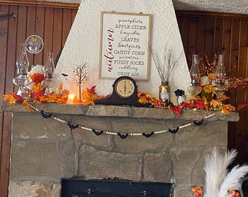 reviewer's mantel with colorful fall leaves on top and the garland hanging below 
