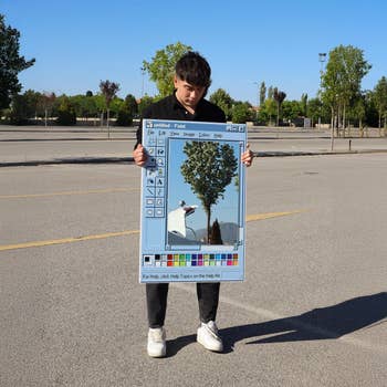 Person holding an oversized faux Paint programme  framework  with an edited histrion   photograph  successful  an bare  parking area