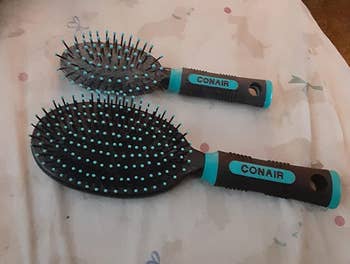 a reviewer's two Conair hairbrushes with black bristles and blue accents