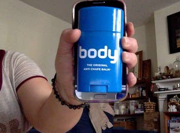 reviewer holding a blue Body Glide container