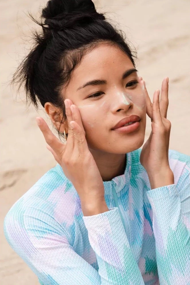 model applying sunscreen on face