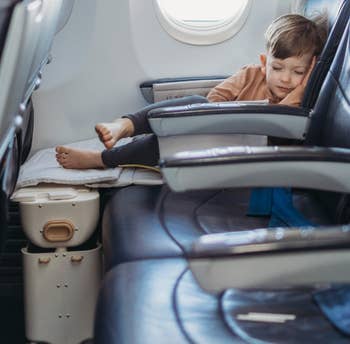 a child model sleeping in a plane seat with legs elevated from the bag