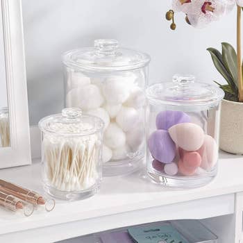 The set of clear apothecary jars filled with cotton swabs and balls and makeup sponges