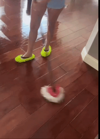 Model using a mop to clean the floors while wearing green mop slippers on their feet 