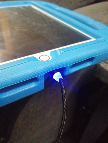 Reviewer image of an iPad being charged by lit up cord 