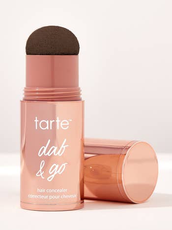Tarte concealer in a pink tube with a sponge applicator, next to its cap, against a light backdrop