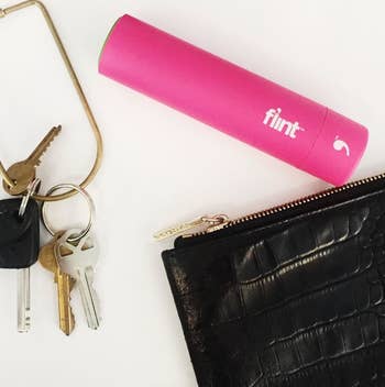 the pink lint roller next to keys and a black purse