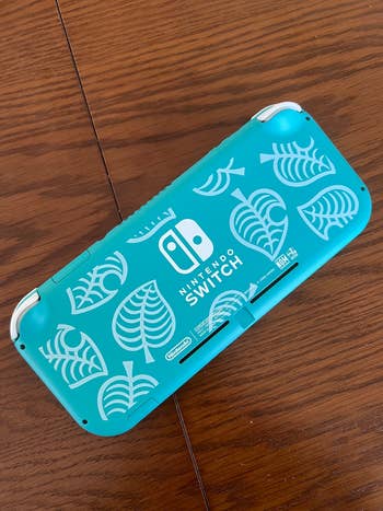 Nintendo Switch case with tropical leaf pattern, on wooden surface