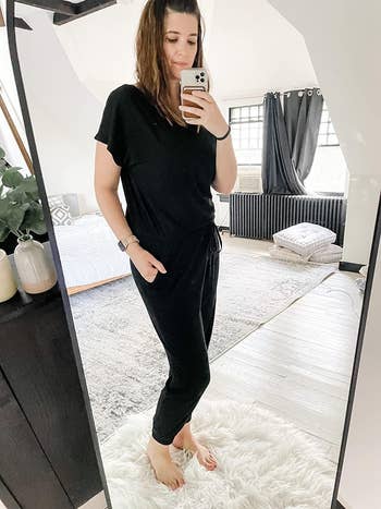 Person taking a mirror selfie wearing a casual black outfit with a tied waist, likely showcasing fashion for shopping content