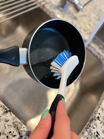reviewer using the brush to clean a small pot