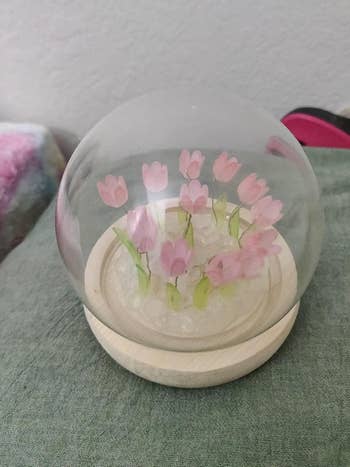 Glass dome with pinkish  tulip figurines connected  a woody  base, suitable for location  decor oregon  a gift