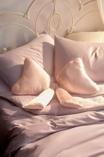 Silk furniture  acceptable   with 2  heart-shaped pillows connected  a neatly made furniture  with an ornate headboard