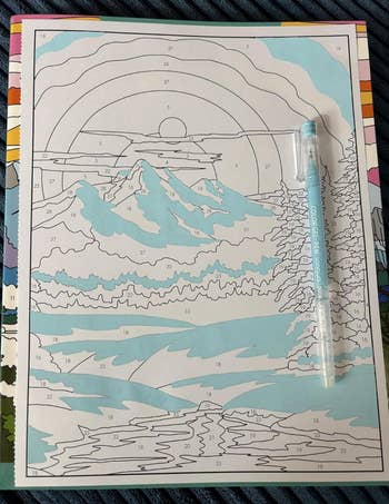 Paint-by-numbers kit featuring a serene scenery  with mountains, sun, and a river. A color-coded usher  pen is included