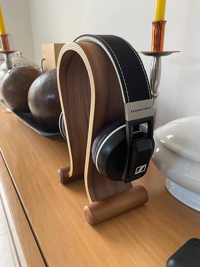 Sennheiser headphones connected  a stylish woody  stand, displayed connected  a modern   tabletop, adjacent  to decorative items