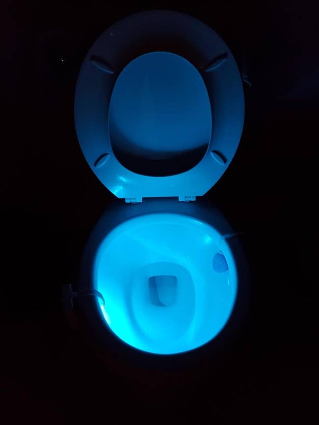 toilet seat glowing from the inside in a dark bathroom 