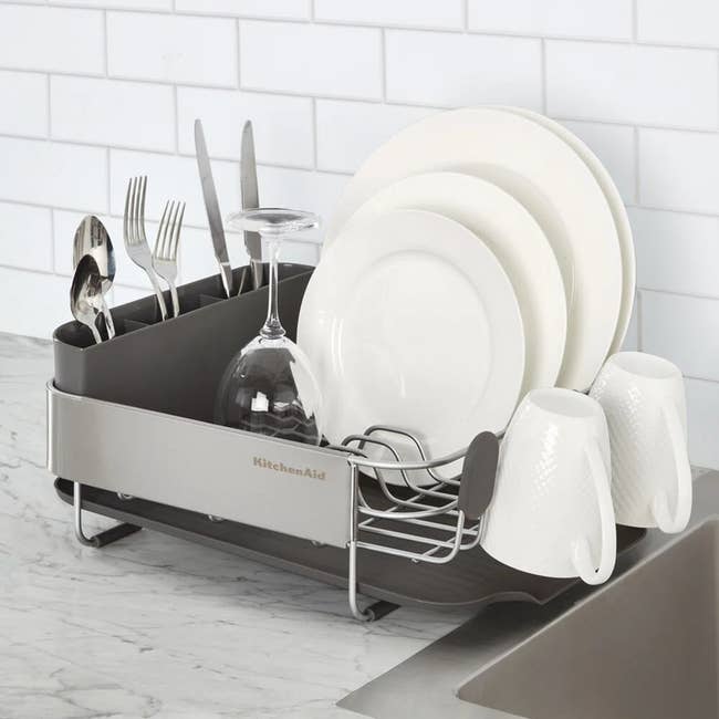 Dish rack on counter with plates, glasses, and utensils neatly arranged, showcasing organized kitchen storage