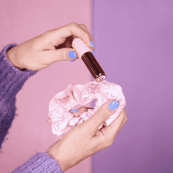 Gif of hands inserting bullet vibrator into pink scrunchie case
