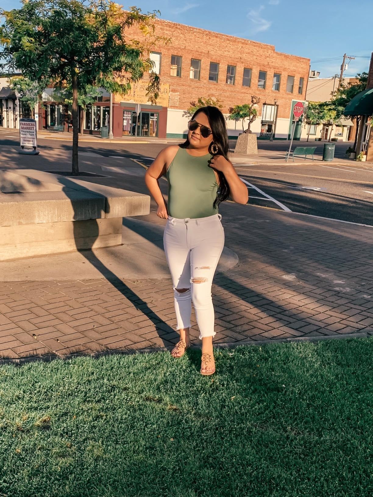 reviewer wearing the olive green bodysuit under white distressed jeans
