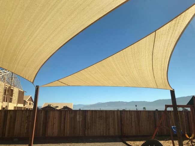 reviewer's two beige sunshade triangles in the yard