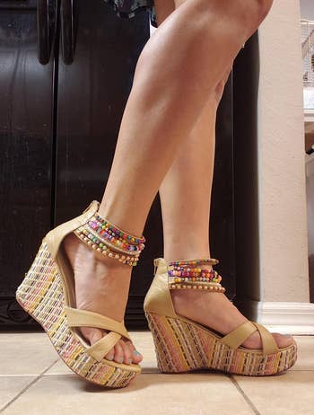 Person wearing colorful, beaded ankle-strap wedge sandals connected a tiled floor